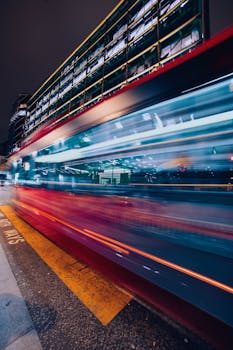 Blurred motion of a double-decker bus in London's vibrant cityscape captured at night.