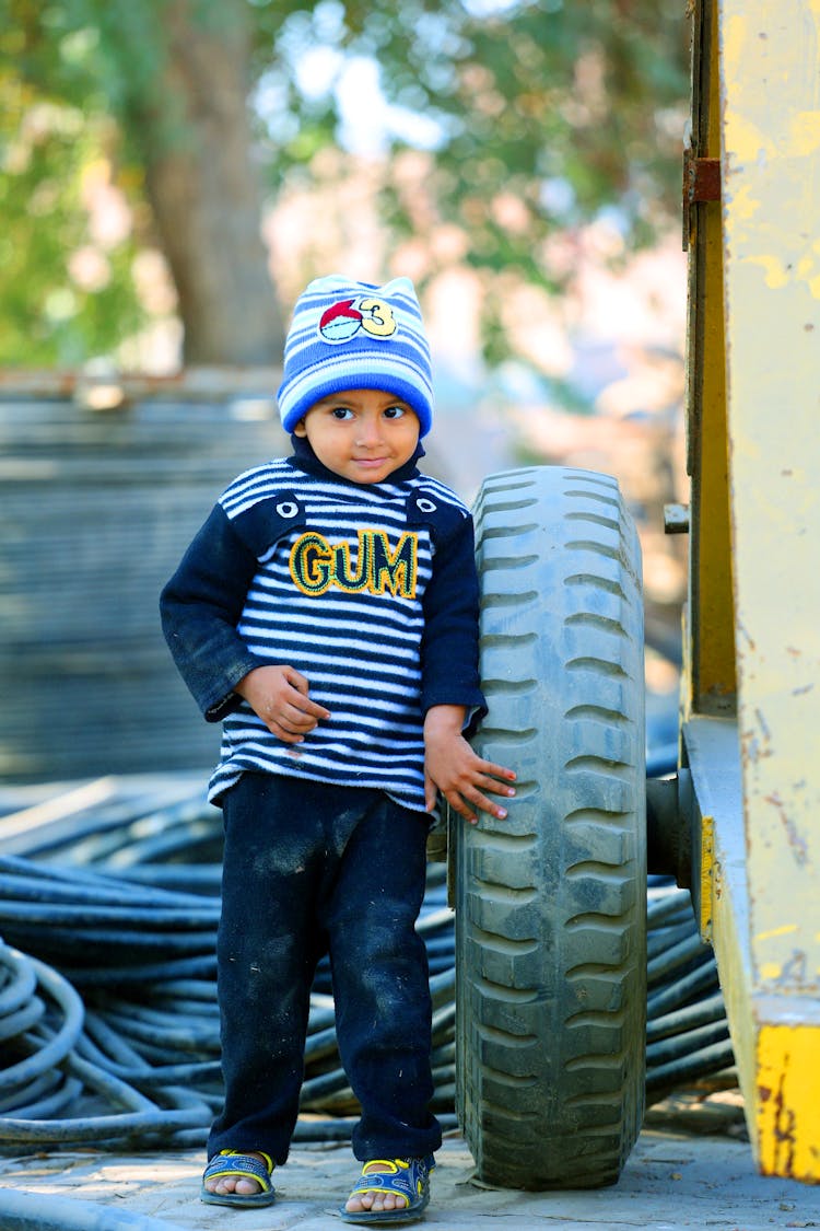 Boy Standing Beside A Tire