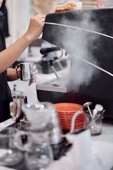 Barista steaming milk using an espresso machine in a trendy cafe.
