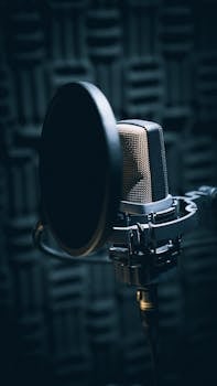 Close-up of a professional microphone with pop filter in a soundproof studio.