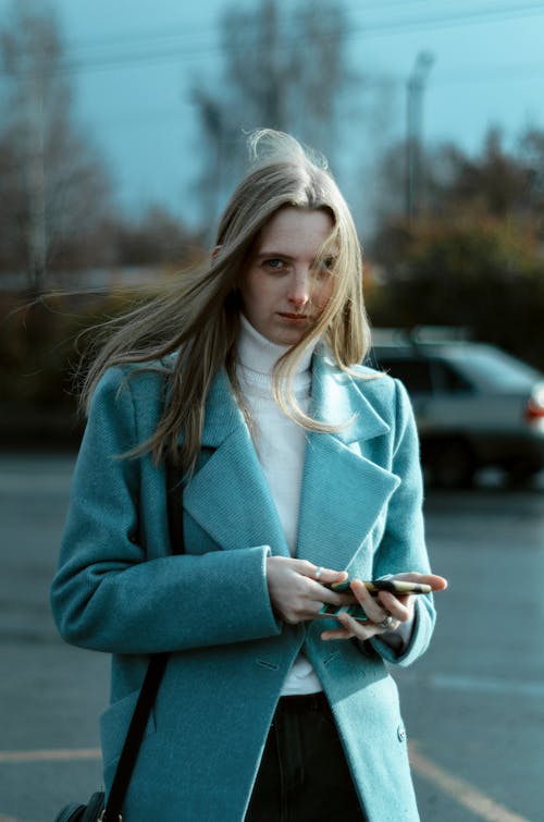 A Woman Wearing Coat Holding a Cellphone