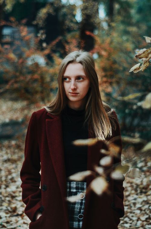 Free Woman in burgundy coat in autumn park, looking thoughtful. Stock Photo