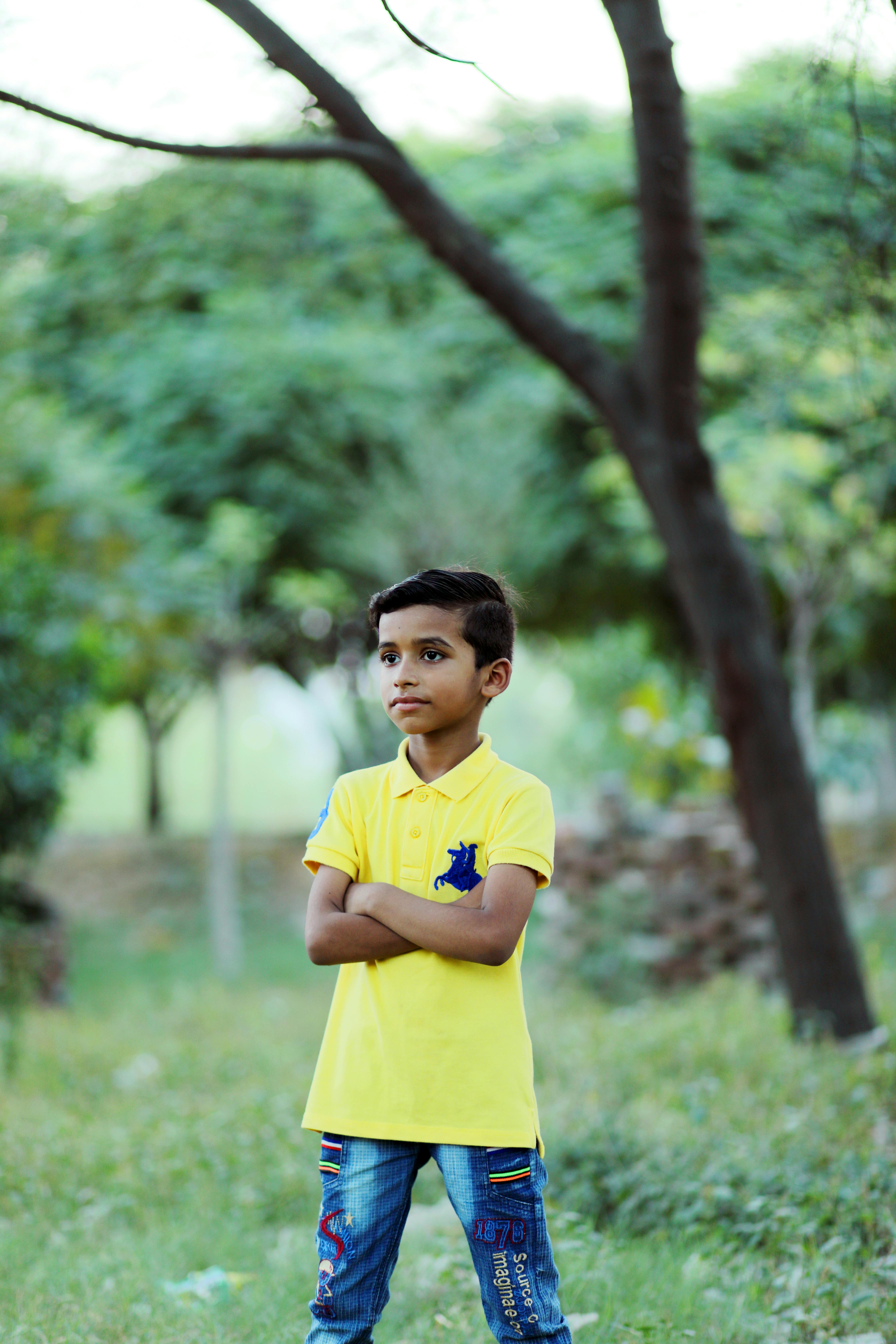 Boy in Yellow Polo Shirt Standing with Arms Crossed on Grass · Free Stock Photo