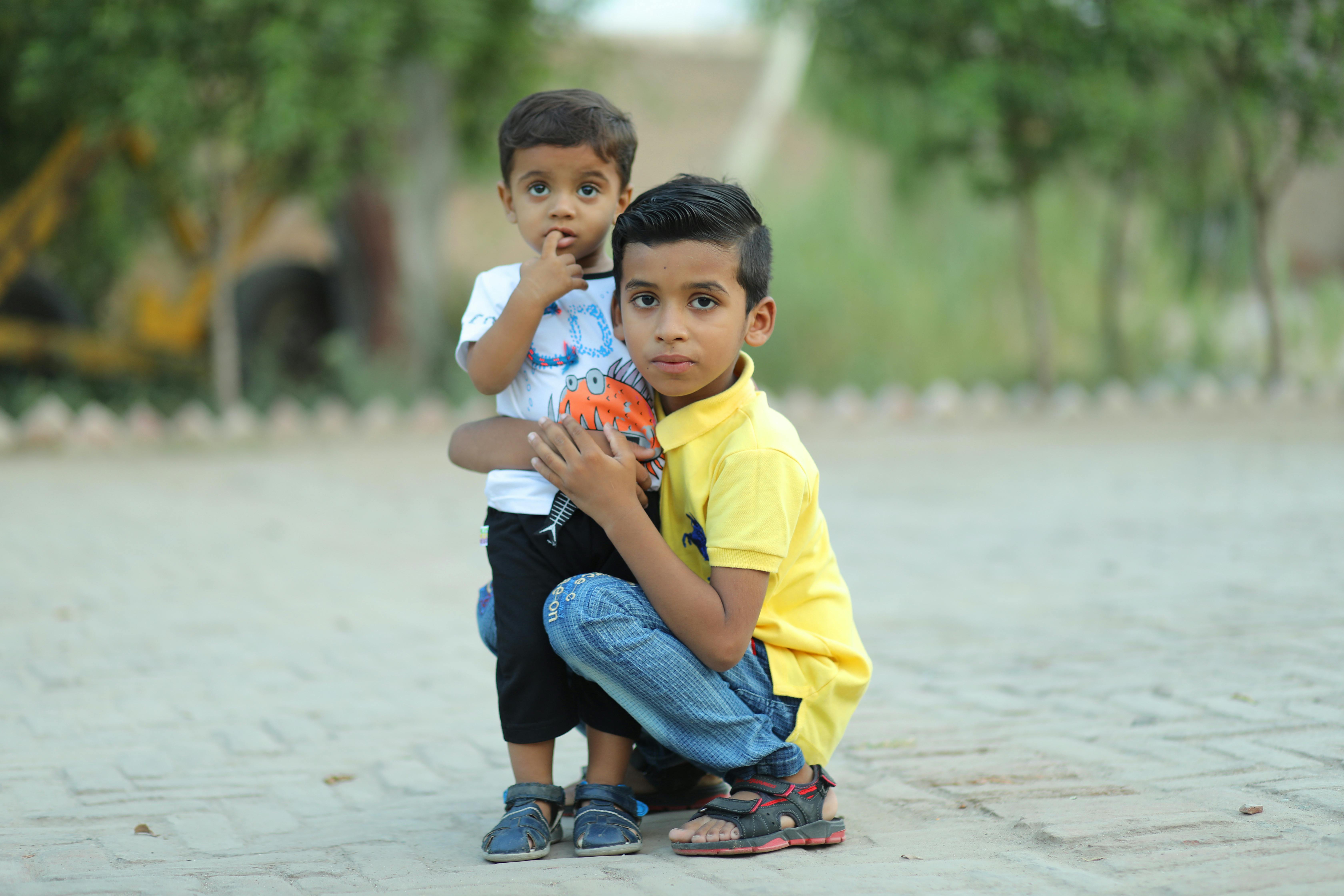 Two young boys embracing outdoors on a sunny day. Captures childhood bond and innocence.