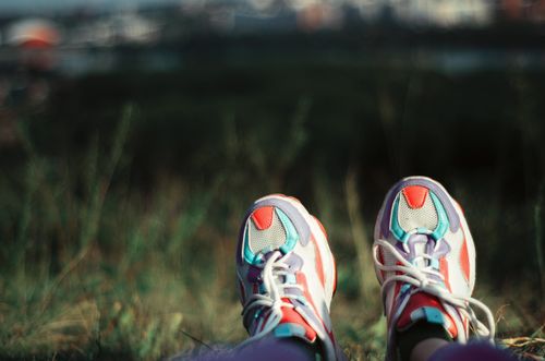 Free Close-up of colorful sneakers as a person relaxes outdoors with a blurred natural background. Stock Photo