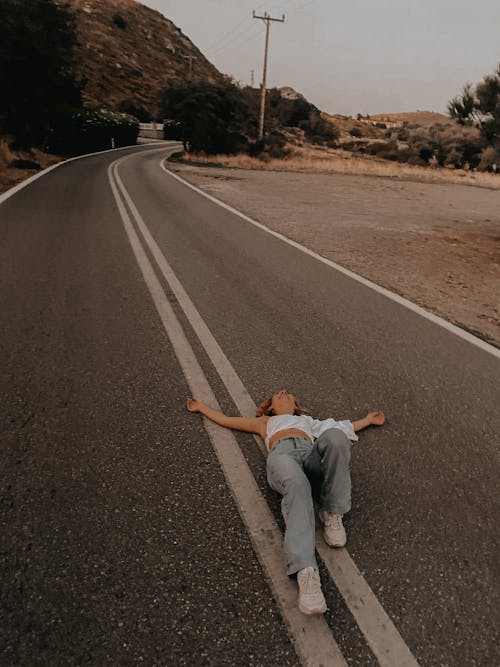 A Woman Lying on the Concrete Road Near the Mountain