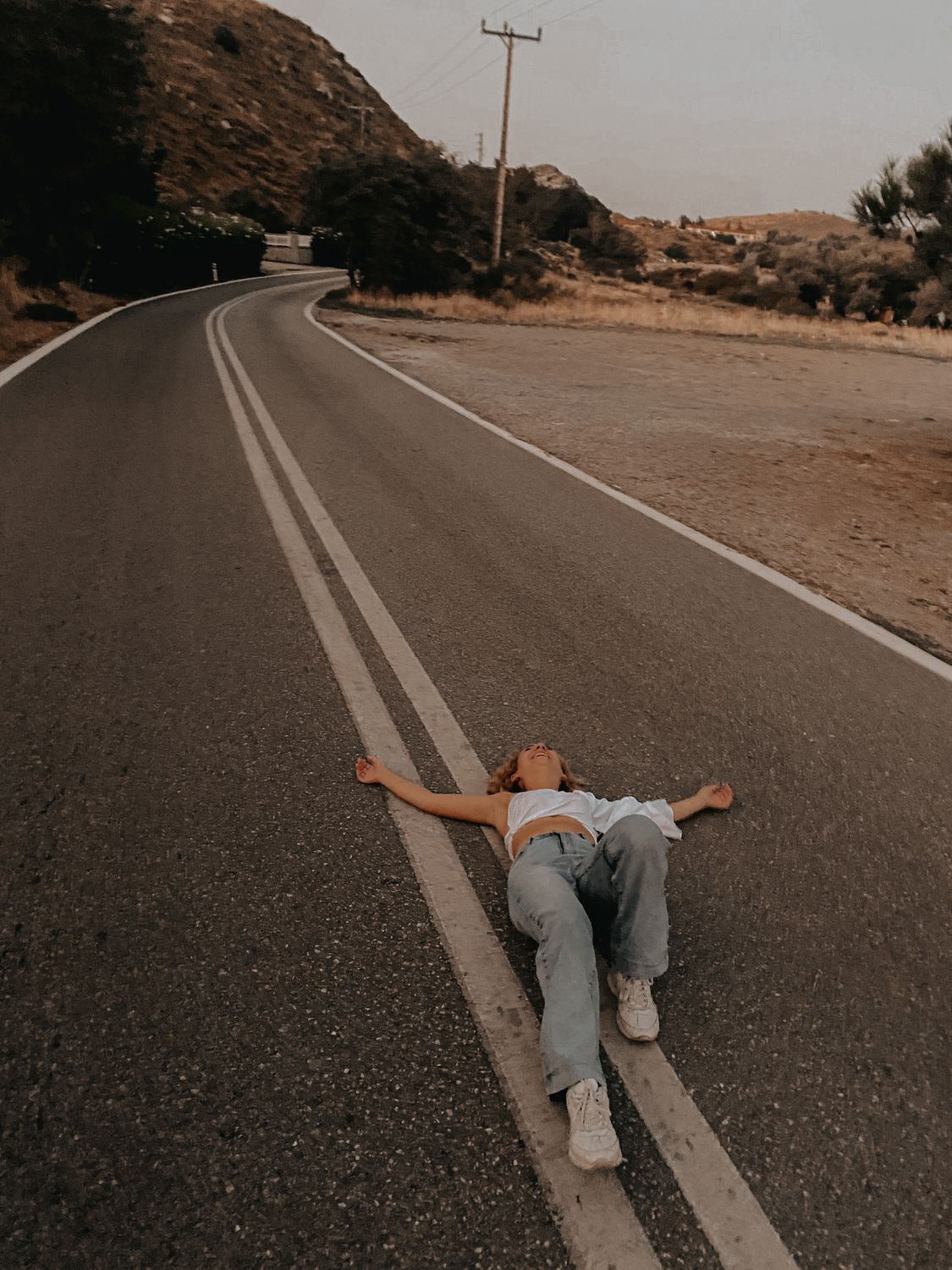 A Woman Lying on the Concrete Road Near the Mountain · Free Stock Photo