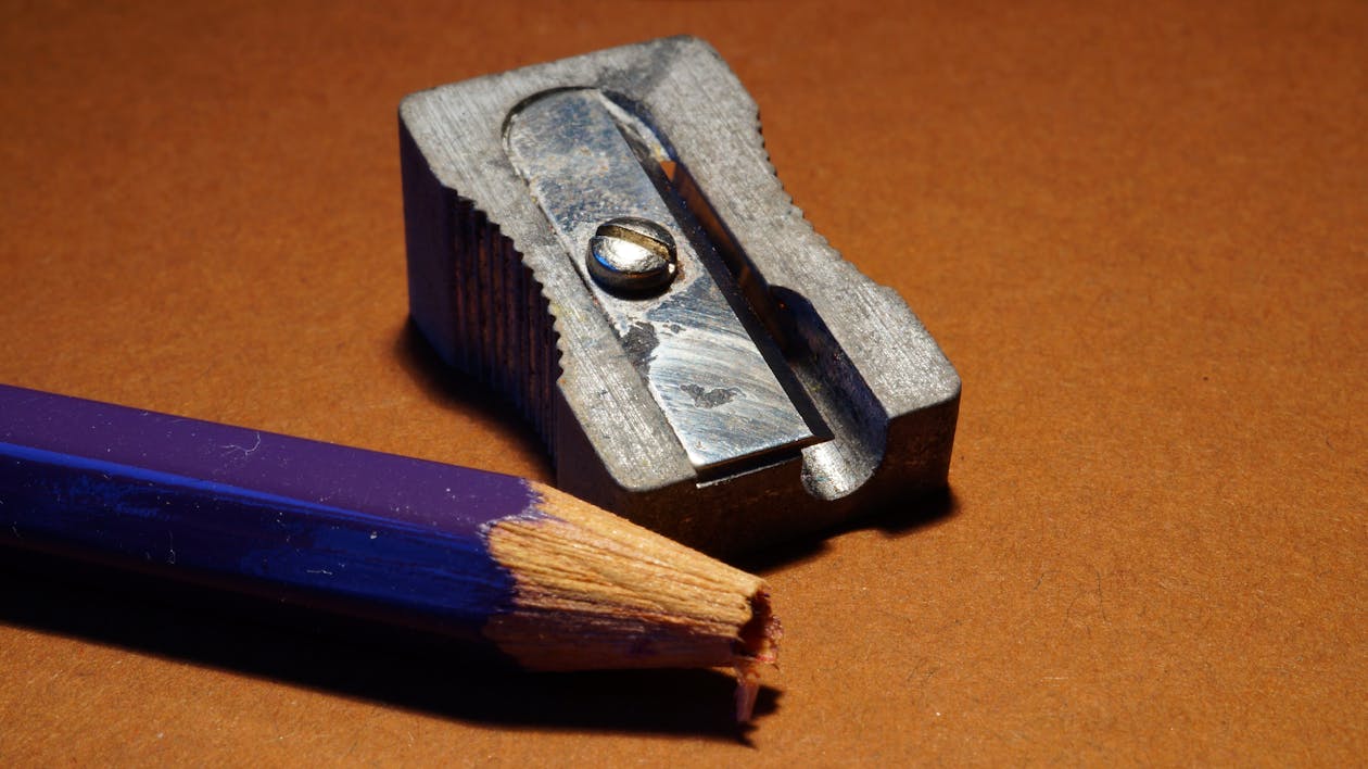Blue Pencil Beside Gray Sharpener on Brown Surface