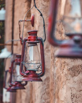 Close-up of vintage red kerosene lanterns hanging against a rustic stone wall, creating a classic ambiance.
