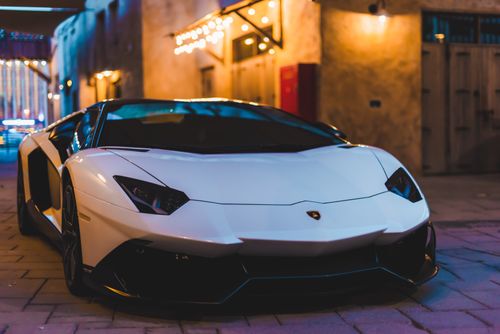 Free White sports car with sleek design parked in an urban night setting with ambient lighting. Stock Photo