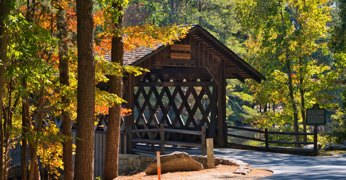 Charming covered bridge surrounded by vibrant autumn foliage at Stone Mountain Park, Georgia.