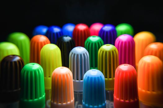 Colorful close-up of various felt-tip pen caps arranged in an artistic pattern.