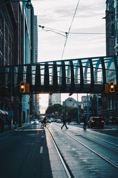 View of a bustling urban street in downtown Toronto featuring a modern overpass and traffic lights.