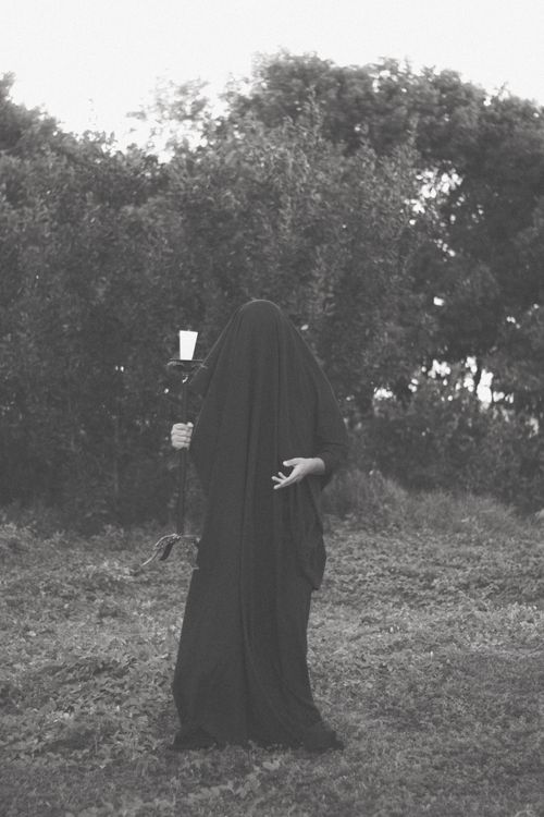 Free A ghostly figure in black with a candle, creating a haunting outdoor atmosphere. Stock Photo