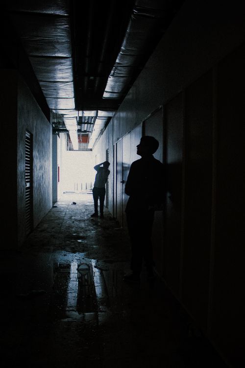 Free Silhouetted figures exploring a dark, eerie corridor in an abandoned building. Stock Photo