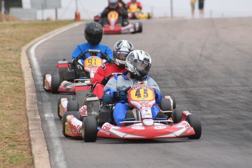 Free Go-kart racers compete on a curving track, showcasing speed and skill. Stock Photo