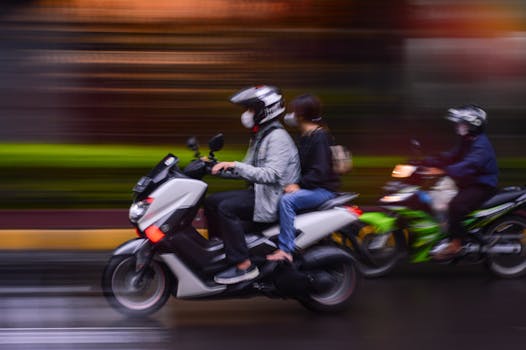 Blurred motion capture of people on scooters rushing through city streets, evoking urban mobility.