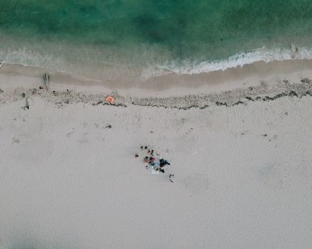 Drone shot capturing the pristine Juan Dolio beach with people relaxing by the shore.