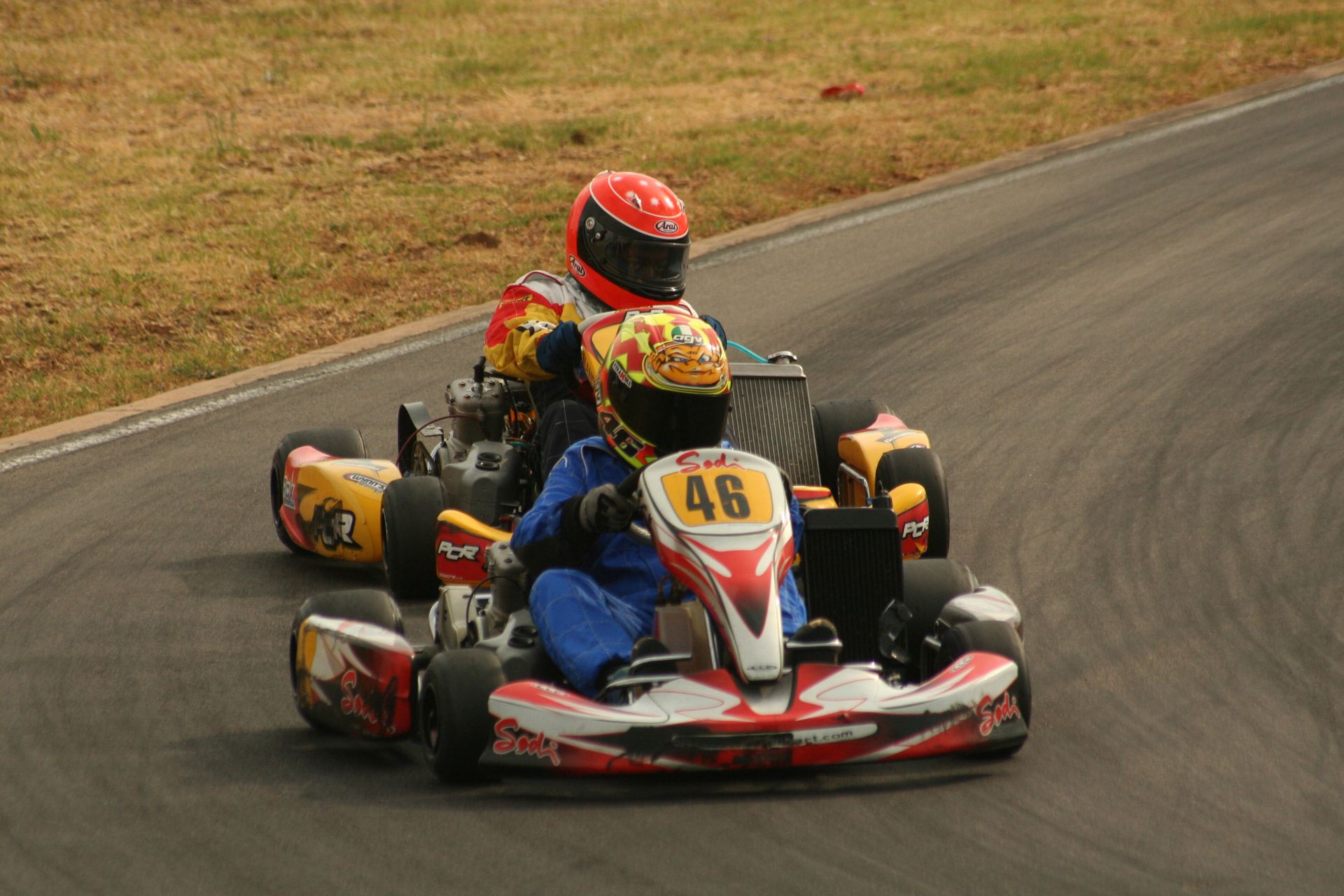 Close-up action shot of two go-kart racers competing on a curving race track.