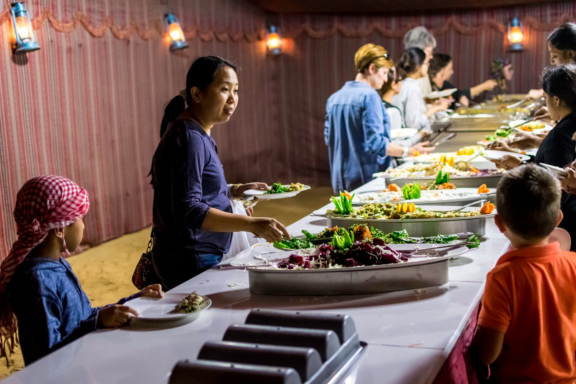 Diverse group enjoying an indoor buffet with vibrant food displays.