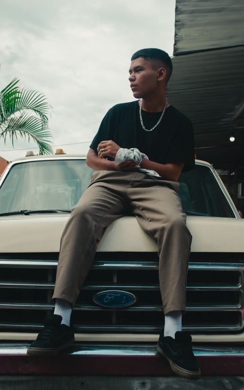 Free Stylish young man in black shirt seated on a vintage pickup truck outdoors in Mexico. Stock Photo