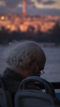 Senior man gazing out over sunset waters, immersed in reflection during a tranquil journey.