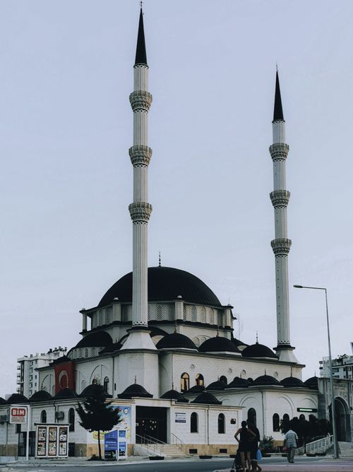 Free Elegant mosque facade with tall minarets against a clear sky, showcasing Islamic architecture. Stock Photo