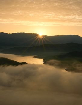 Serene sunrise over mist-covered lake and mountains in Albania, capturing nature's tranquil beauty.