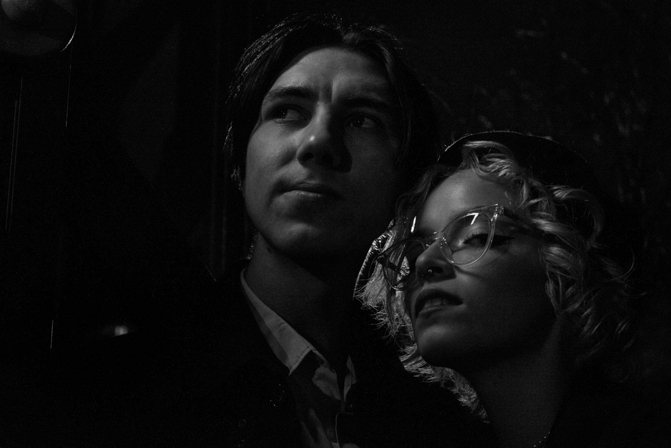 Artistic black and white portrait of a couple sharing a moment in a thoughtful pose, captured with dramatic lighting.