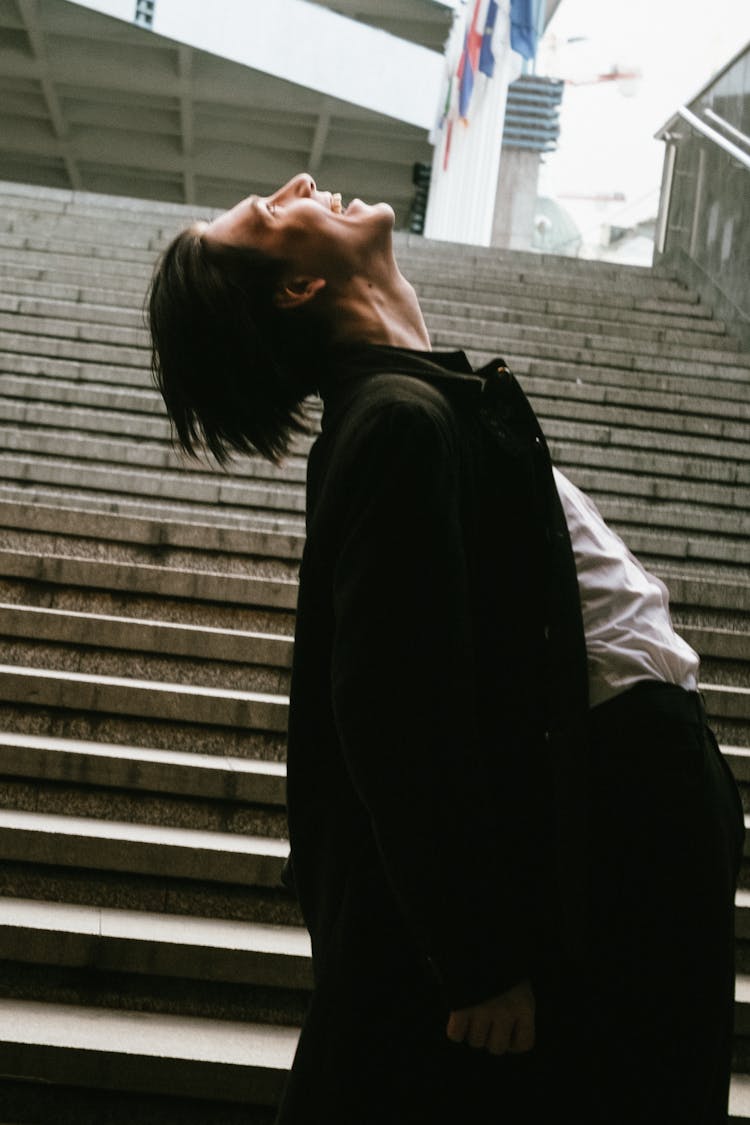 Young Man Standing On Steps And Laughing With His Head Back 