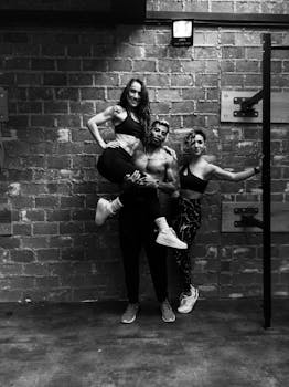 Three athletic individuals pose energetically in a gym, showcasing fitness and teamwork.