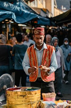 A street vendor in traditional attire selling snacks in a bustling outdoor market.