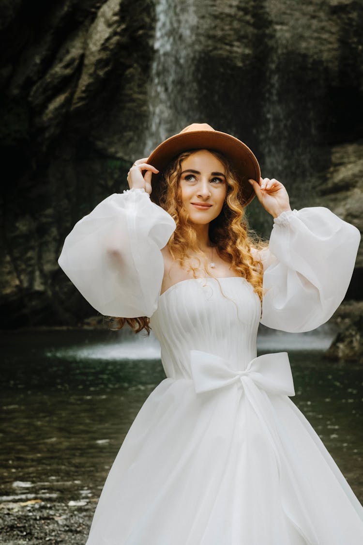 Woman In Hat And Dress With Waterfall In Background