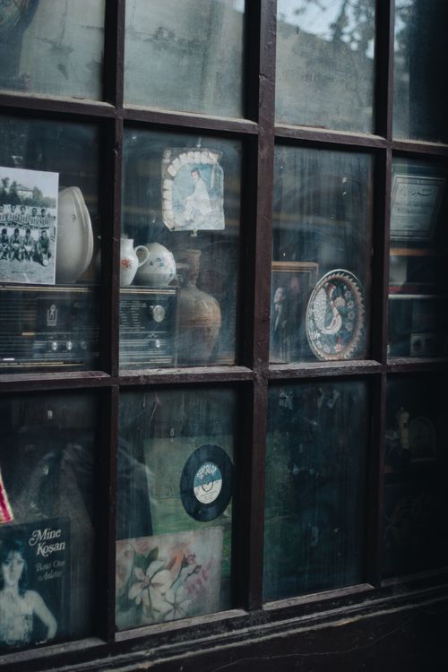 Free A vintage storefront window displaying an array of antique collectibles and porcelain items. Stock Photo