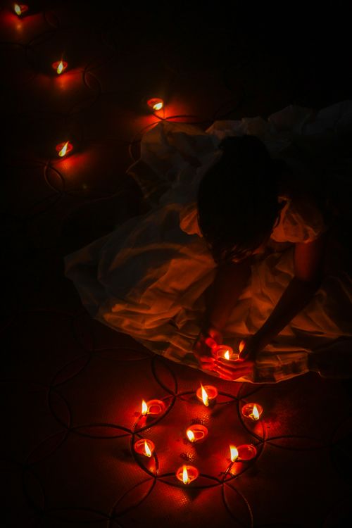 Free A woman arranges oil lamps during a nighttime Diwali celebration in Madikeri, India. Stock Photo