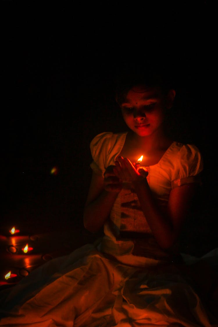 Girl Sitting In The Dark And Holding A Candle 