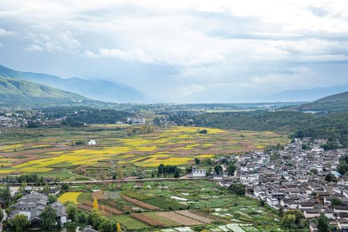 Free Expansive landscape of fields and a small town with mountains in the background. Stock Photo