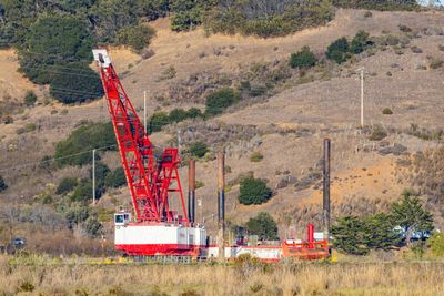 Large red crane at a construction site in a hilly rural landscape