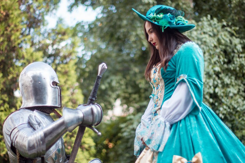 A lady and knight in period costumes in a park setting, capturing a classic medieval vibe.