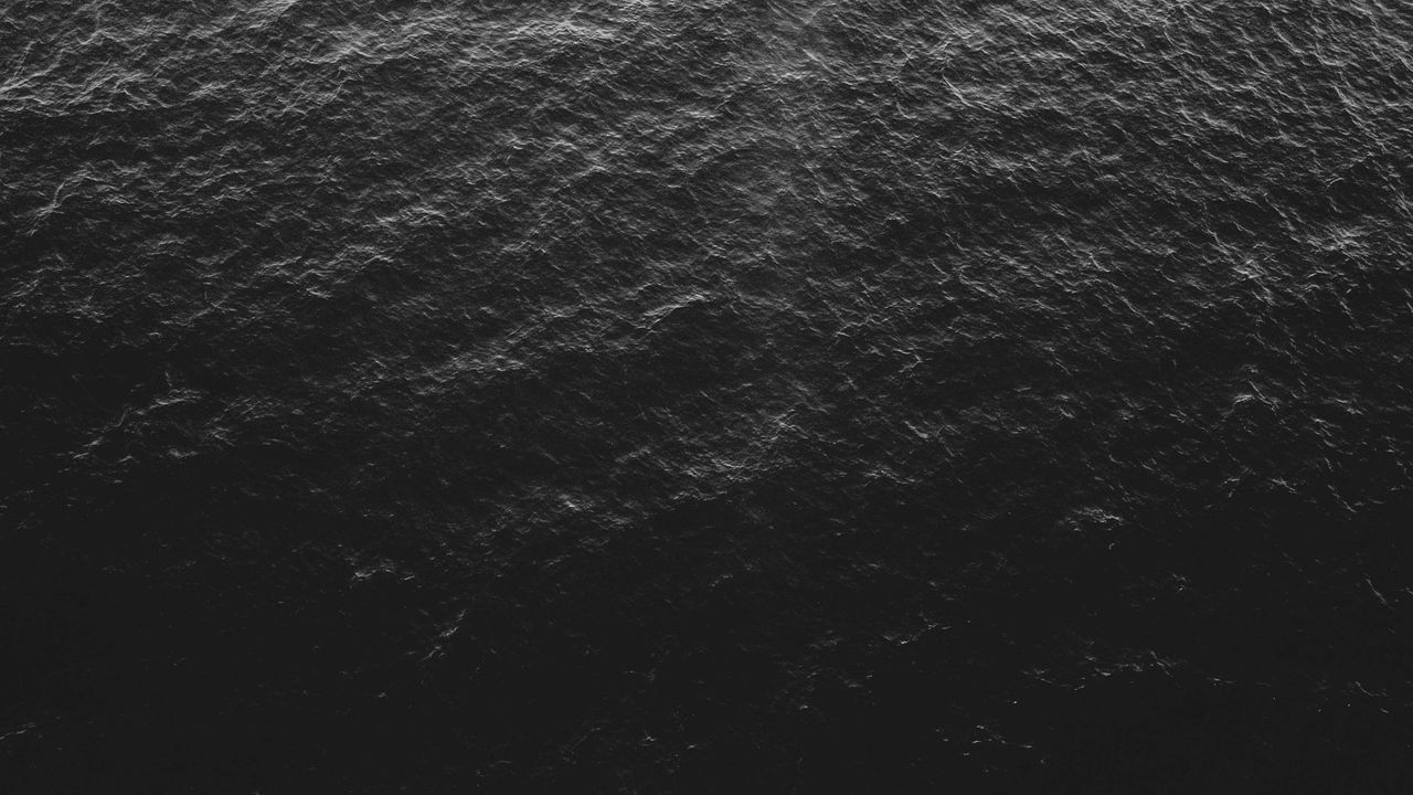 aerial view of dark textured ocean surface in monochrome tones depicti