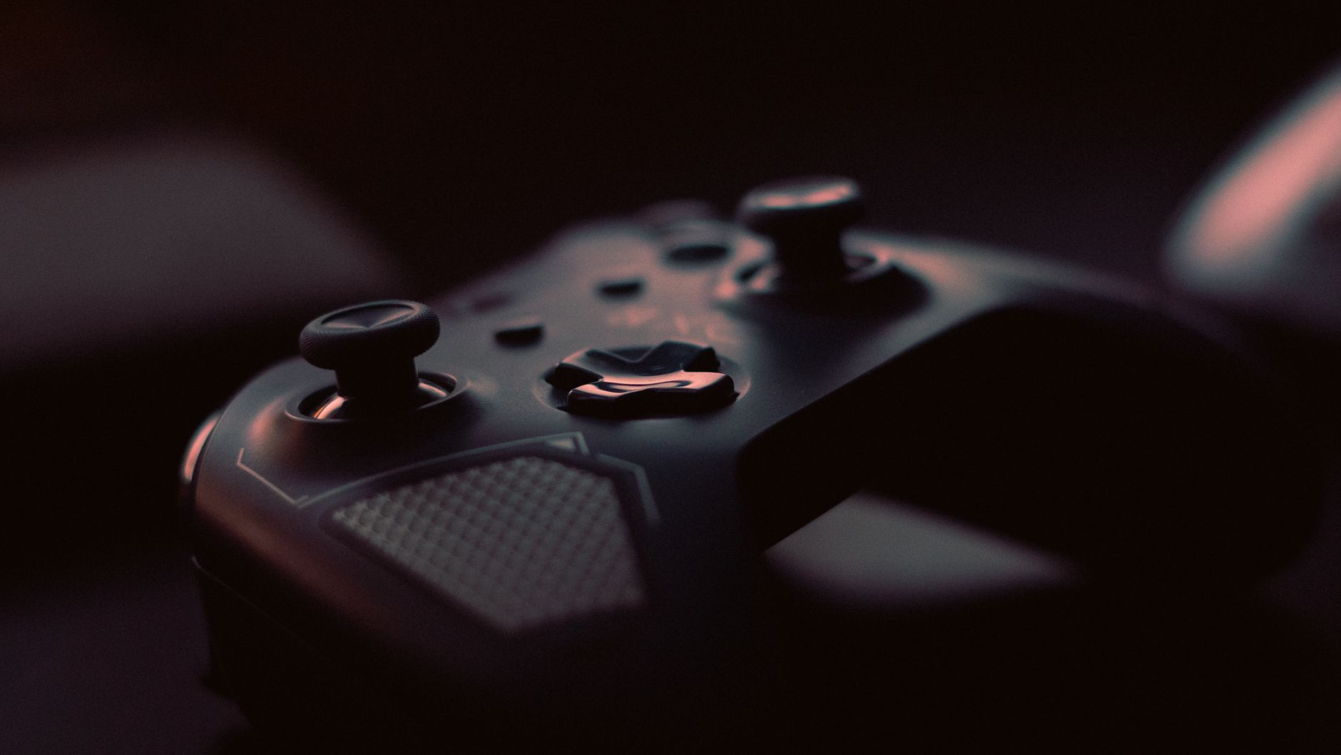 A close-up shot of a game controller in low light, highlighting its design and buttons.