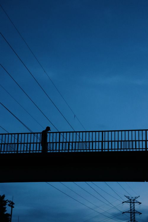 Free A solitary figure silhouetted on a bridge against a night sky, Medellín. Stock Photo