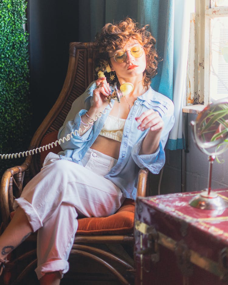 A Woman Sitting On Brown Wooden Chair Holding Telephone