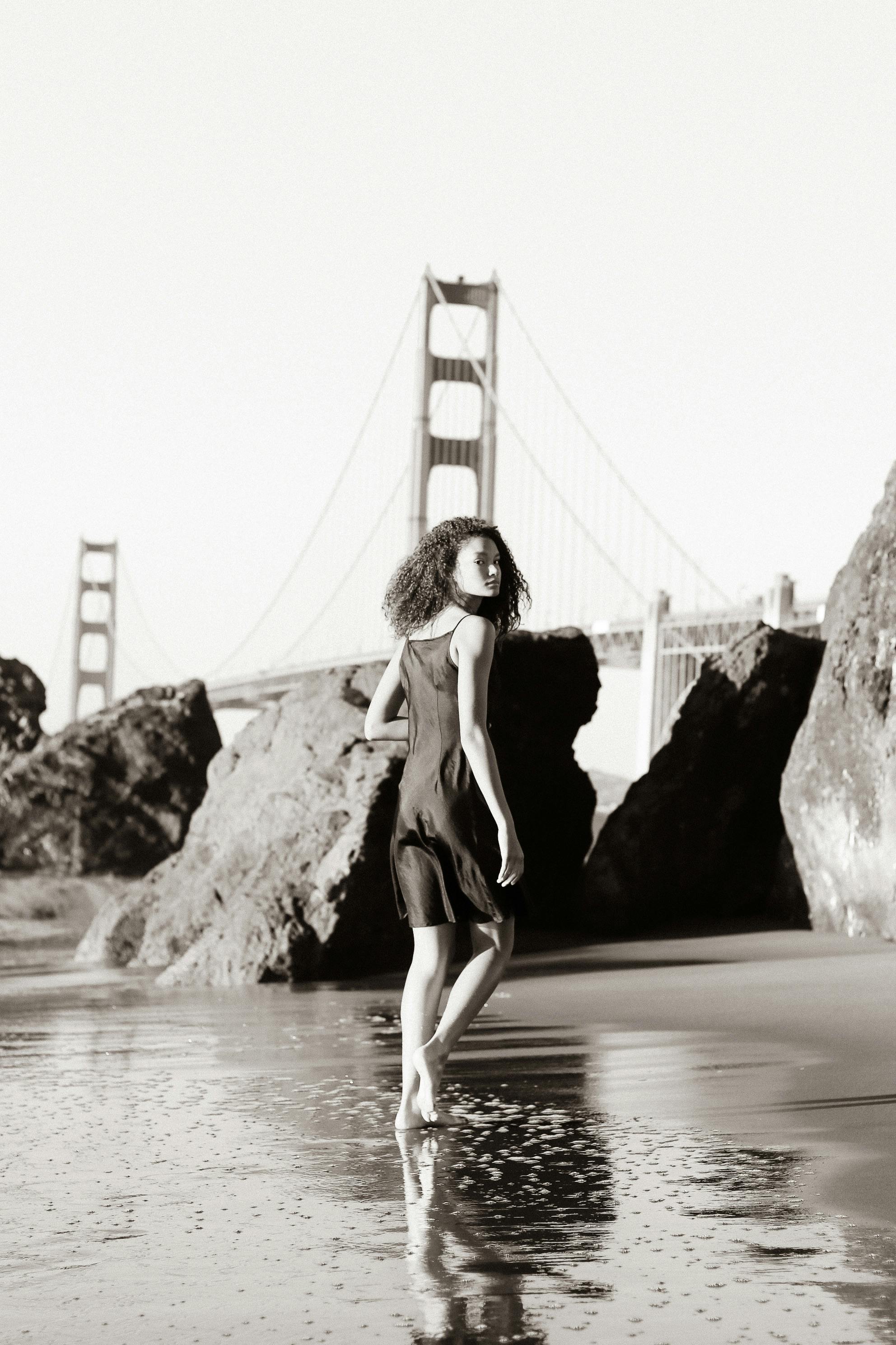 a woman in black dress standing on the beach