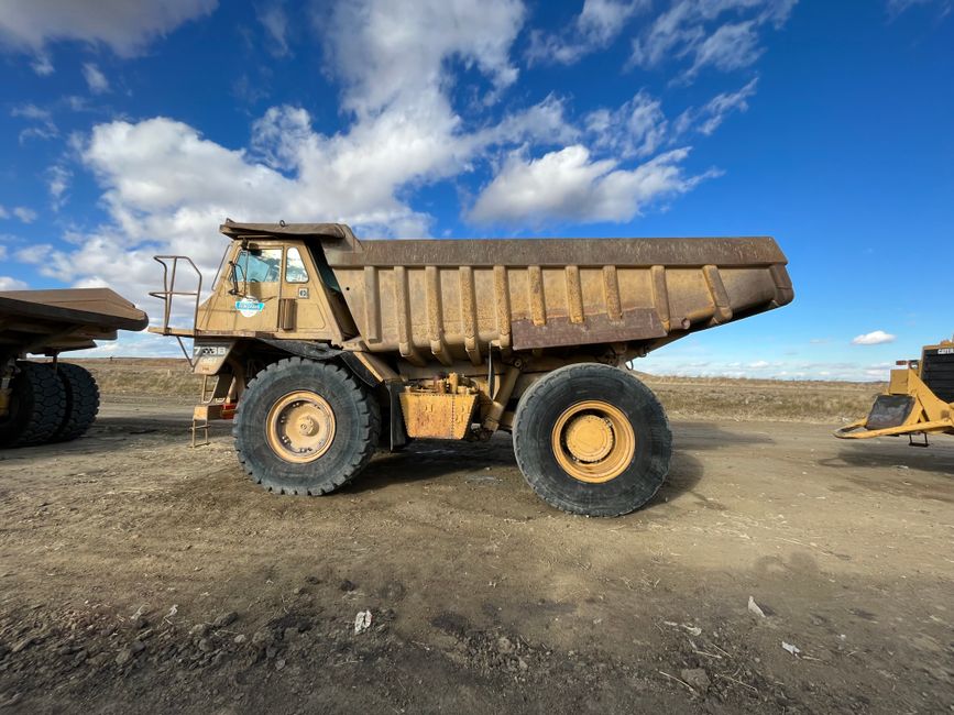Gigantic dump truck parked at a construction site under a clear blue sky.