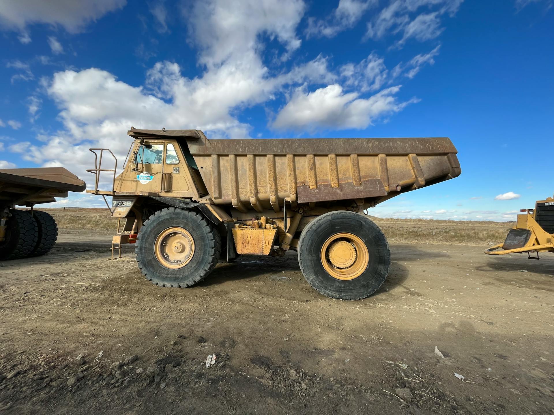 Gigantic dump truck parked at a construction site under a clear blue sky.