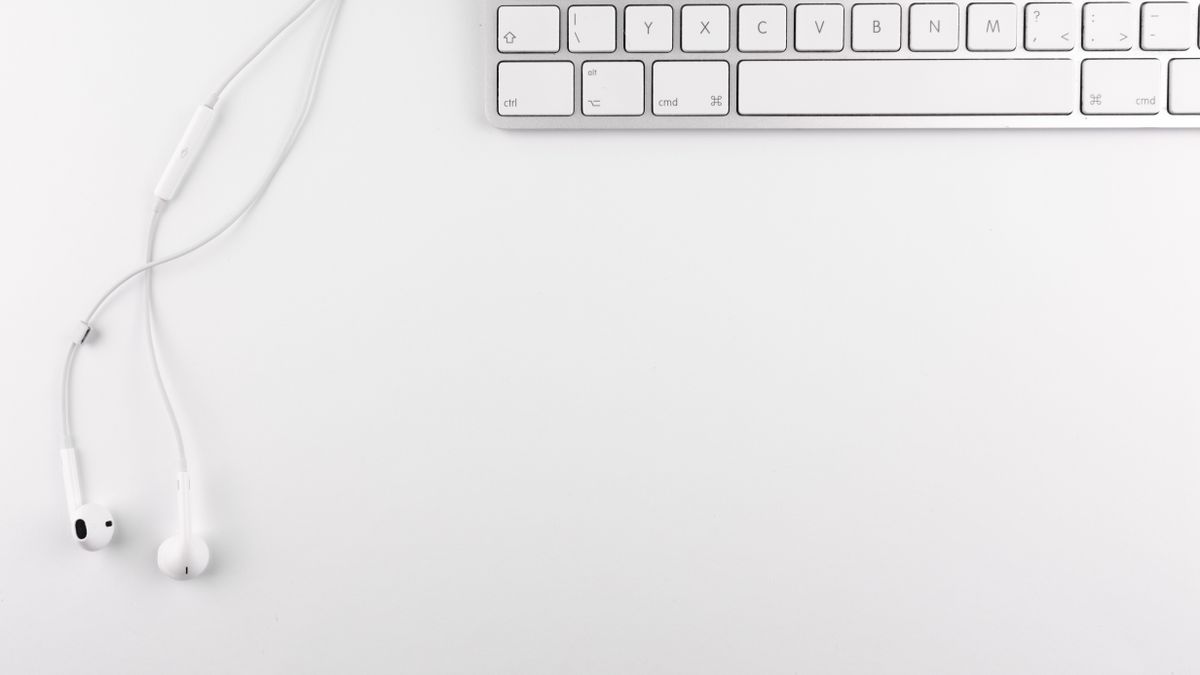 A keyboard and earphones on a clean desk