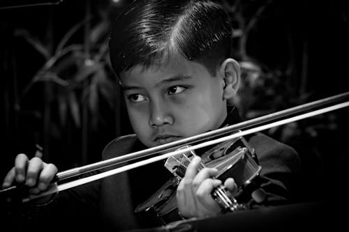 Grayscale Photo of a Boy Playing the Violin
