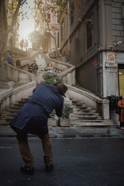 Photo of a Man Taking Picture of a Woman Posing on a Stairs