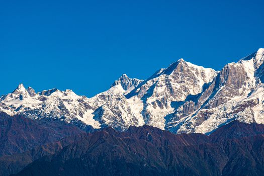Breathtaking view of snowcapped mountains with a clear blue sky, showcasing natural power and beauty.